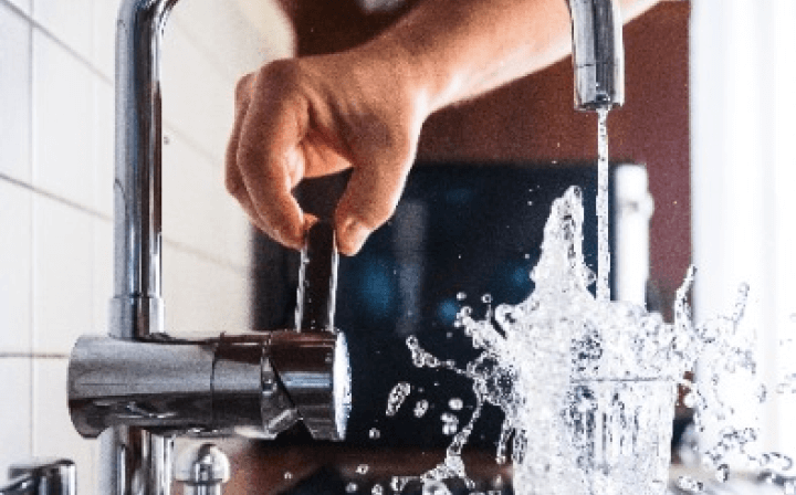 写真：蛇口をひねってコップに水を入れている